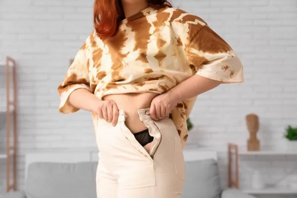 Image of woman trying to do her trousers up after pregnancy weight gain Wincanton