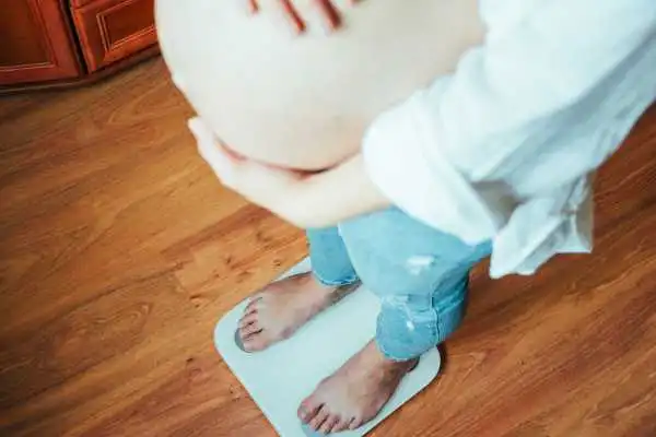 Image of woman weighing herself and experiencing weight gain through pregnancy Wincanton